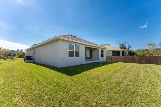 rear view of property featuring a lawn and central AC unit