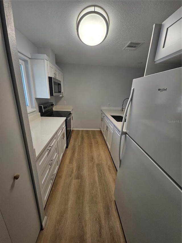 kitchen with sink, appliances with stainless steel finishes, and white cabinets