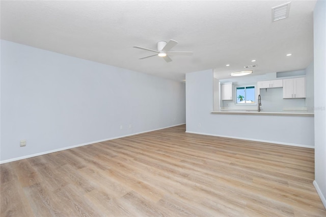 unfurnished living room with light hardwood / wood-style flooring, a textured ceiling, and ceiling fan