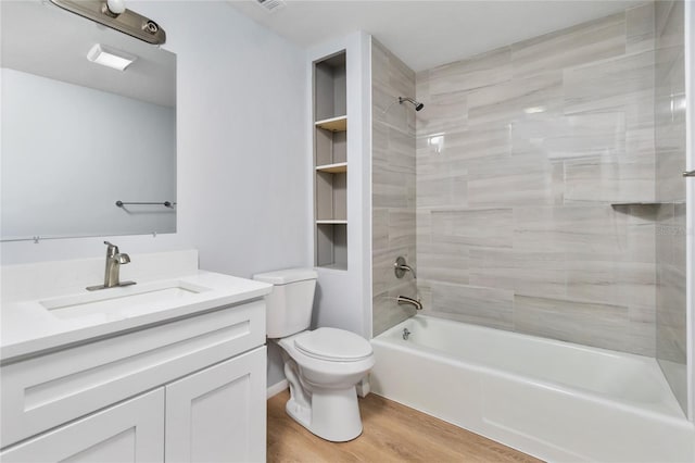 full bathroom featuring vanity, hardwood / wood-style floors, tiled shower / bath combo, and toilet