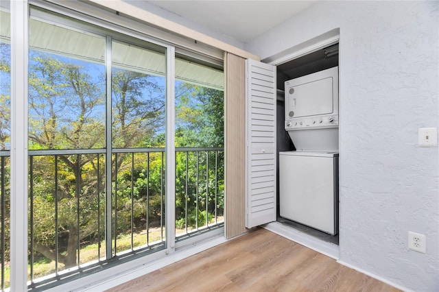 laundry room featuring light hardwood / wood-style floors, a wealth of natural light, and stacked washer and clothes dryer