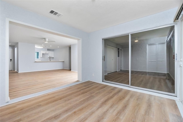 unfurnished living room featuring light hardwood / wood-style flooring, sink, and ceiling fan