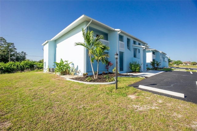 view of side of home featuring a lawn and a balcony