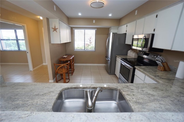 kitchen with white cabinetry, a healthy amount of sunlight, stainless steel appliances, and light tile patterned floors