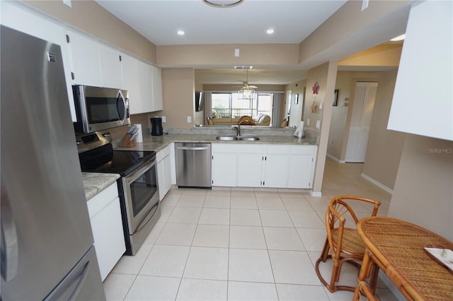 kitchen with appliances with stainless steel finishes, white cabinetry, light tile patterned flooring, and hanging light fixtures