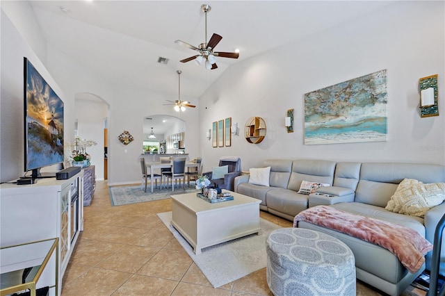 tiled living room with ceiling fan and high vaulted ceiling