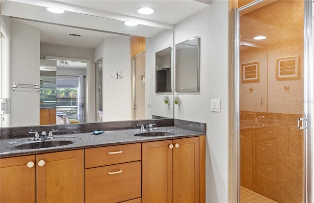 bathroom with a shower with door, vanity, and tile patterned flooring