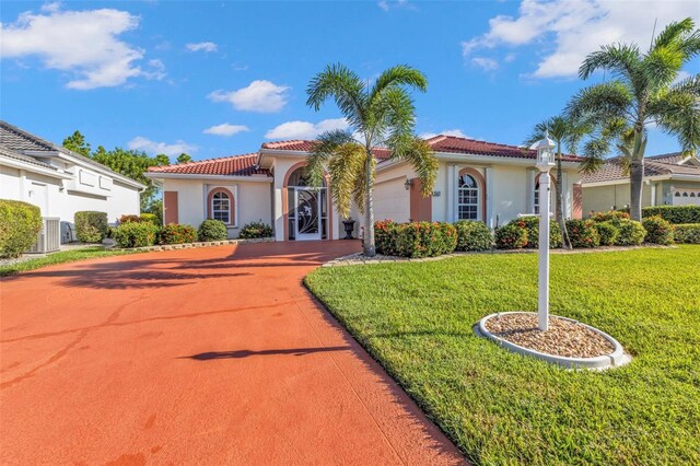 2831 Corinthia Cir, North Fort Myers, FL 33917 - mediterranean / spanish home with a garage, a front yard, stucco siding, concrete driveway, and a tile roof
