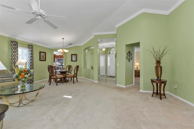 carpeted dining room with ornamental molding and ceiling fan with notable chandelier