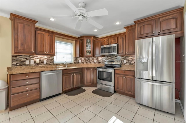 kitchen featuring tasteful backsplash, ceiling fan, appliances with stainless steel finishes, ornamental molding, and stone countertops