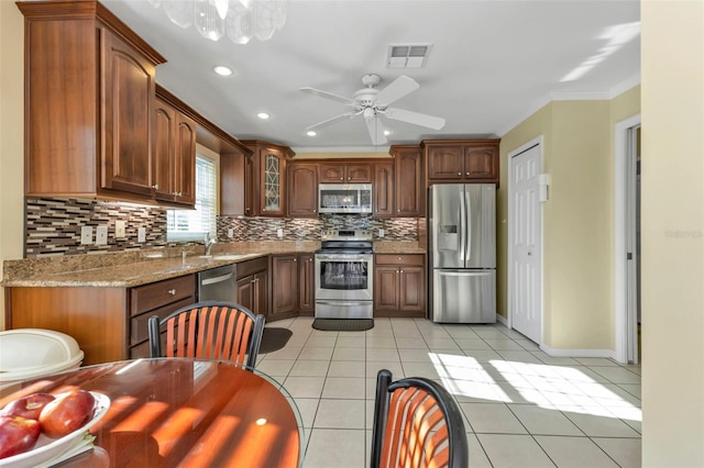 kitchen featuring decorative backsplash, appliances with stainless steel finishes, light tile patterned floors, and ceiling fan