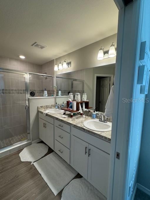 bathroom featuring hardwood / wood-style flooring, vanity, and a shower with door