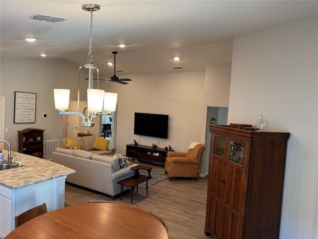 living room with ceiling fan, sink, vaulted ceiling, and light wood-type flooring