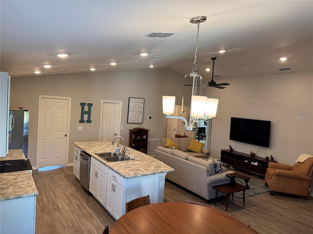 kitchen featuring white cabinets, light stone countertops, an island with sink, decorative light fixtures, and stainless steel appliances