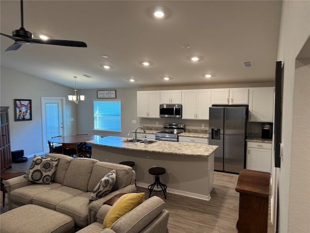 kitchen featuring white cabinetry, an island with sink, stainless steel appliances, and decorative light fixtures