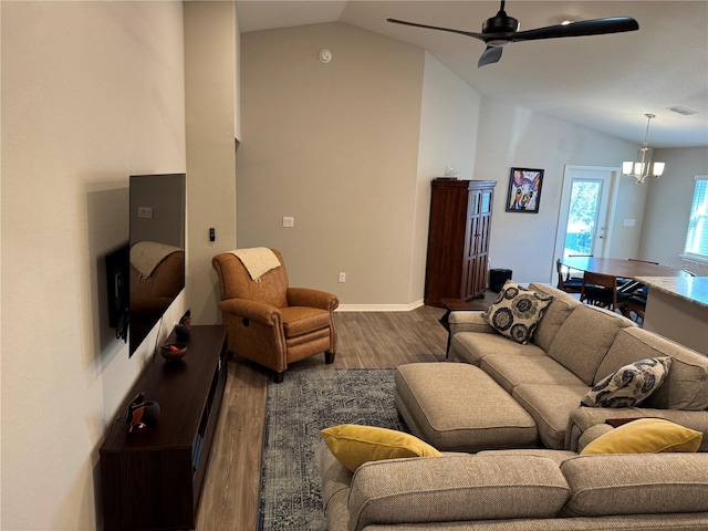 living room with hardwood / wood-style floors, ceiling fan with notable chandelier, and vaulted ceiling