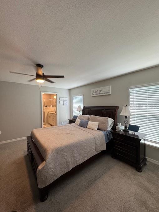 carpeted bedroom featuring multiple windows, a textured ceiling, ensuite bath, and ceiling fan