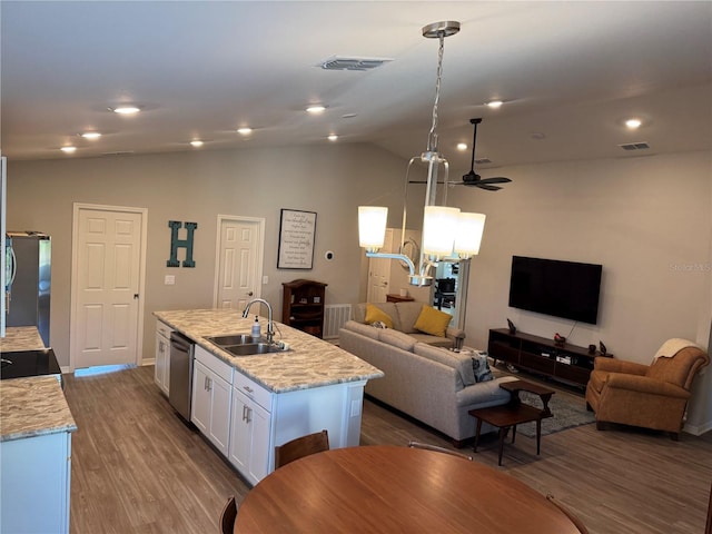 kitchen with a kitchen island with sink, white cabinets, sink, appliances with stainless steel finishes, and decorative light fixtures