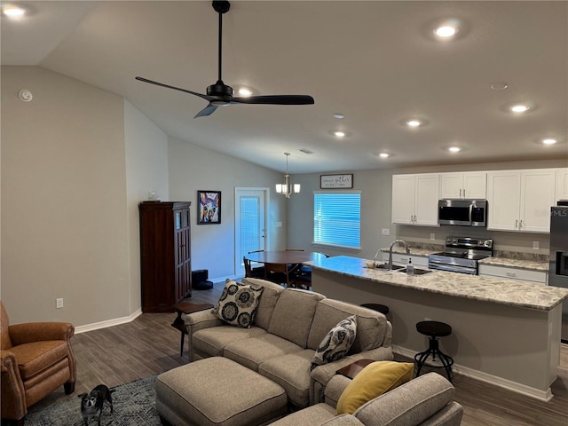 living room featuring ceiling fan with notable chandelier, dark hardwood / wood-style flooring, sink, and vaulted ceiling