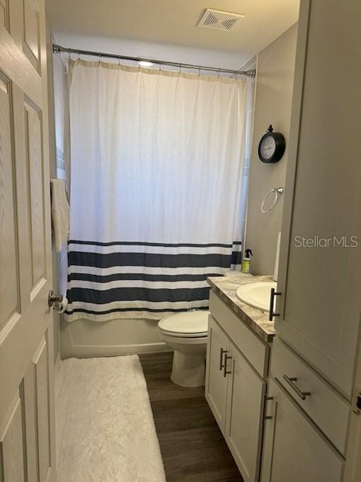 full bathroom featuring hardwood / wood-style flooring, vanity, toilet, and shower / bath combo