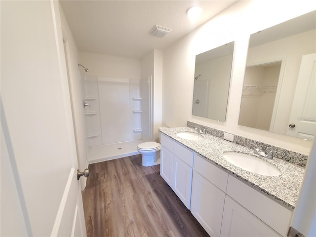 bathroom featuring toilet, vanity, walk in shower, and hardwood / wood-style floors