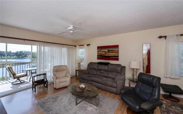 living room featuring ceiling fan, a textured ceiling, a wealth of natural light, and hardwood / wood-style floors