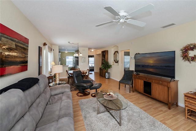 living room featuring light hardwood / wood-style flooring, a textured ceiling, and ceiling fan