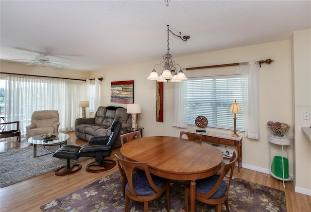 dining space with hardwood / wood-style floors and ceiling fan with notable chandelier