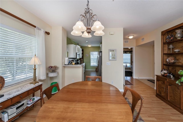 dining area featuring a notable chandelier, light hardwood / wood-style flooring, and plenty of natural light