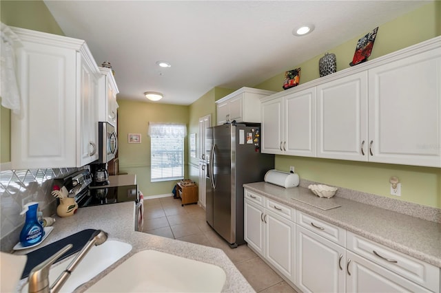 kitchen with white cabinets, stainless steel appliances, backsplash, and light tile patterned floors