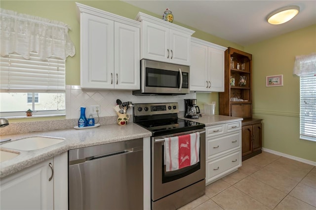 kitchen featuring white cabinetry, stainless steel appliances, a healthy amount of sunlight, and tasteful backsplash