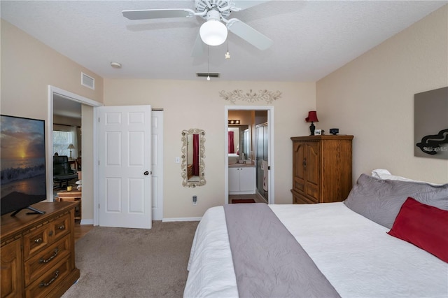 bedroom with a textured ceiling, ensuite bathroom, carpet flooring, and ceiling fan