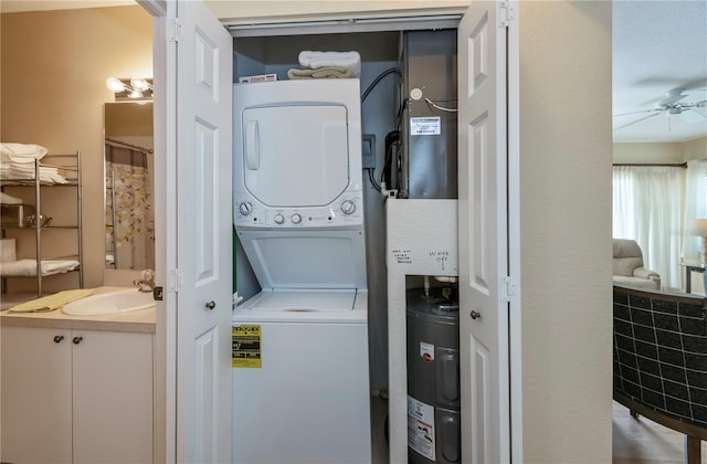 washroom with sink, water heater, ceiling fan, and stacked washing maching and dryer