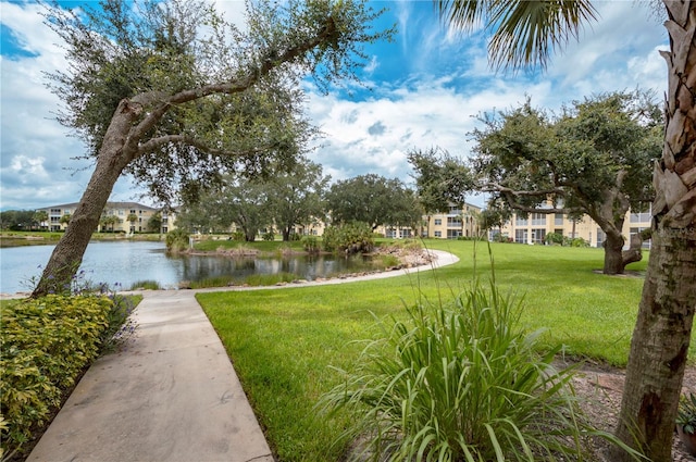 view of home's community with a water view and a lawn