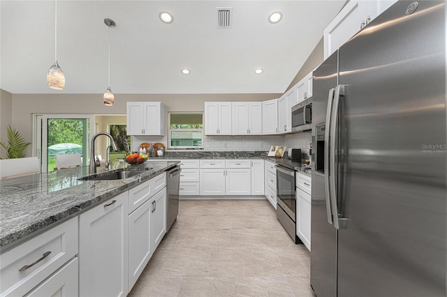 kitchen with hanging light fixtures, sink, white cabinets, appliances with stainless steel finishes, and tasteful backsplash