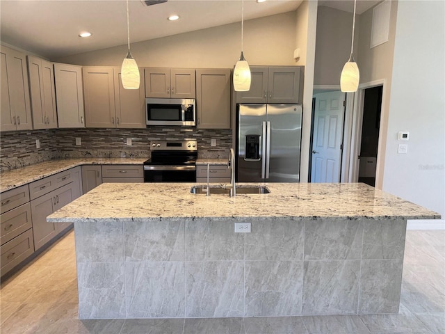 kitchen featuring sink, light stone counters, appliances with stainless steel finishes, and vaulted ceiling