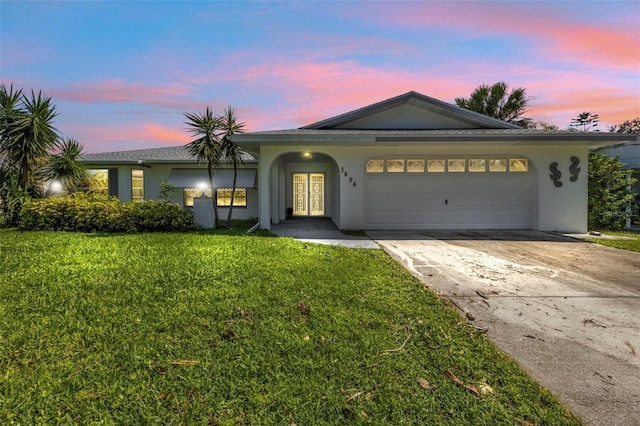 ranch-style house featuring a garage and a lawn