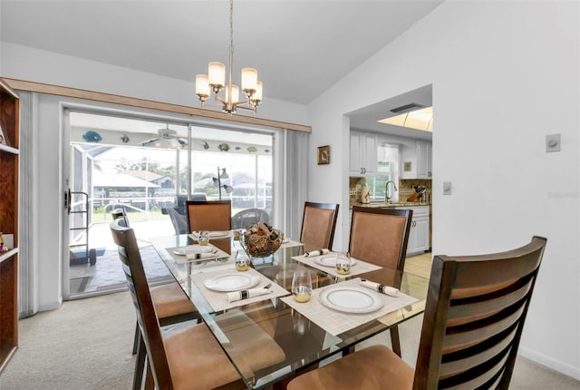 carpeted dining room featuring sink, vaulted ceiling, and a chandelier