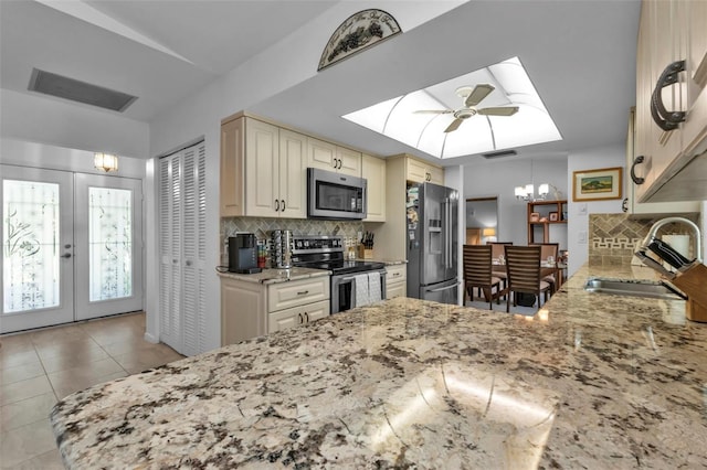 kitchen featuring cream cabinets, sink, ceiling fan with notable chandelier, backsplash, and stainless steel appliances