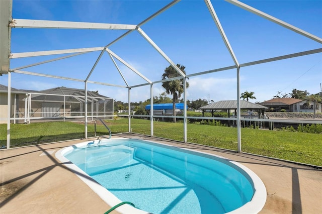 view of swimming pool with a patio, a yard, and glass enclosure