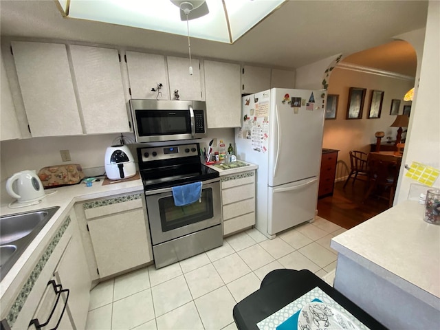 kitchen with ornamental molding, sink, stainless steel appliances, and light tile patterned floors