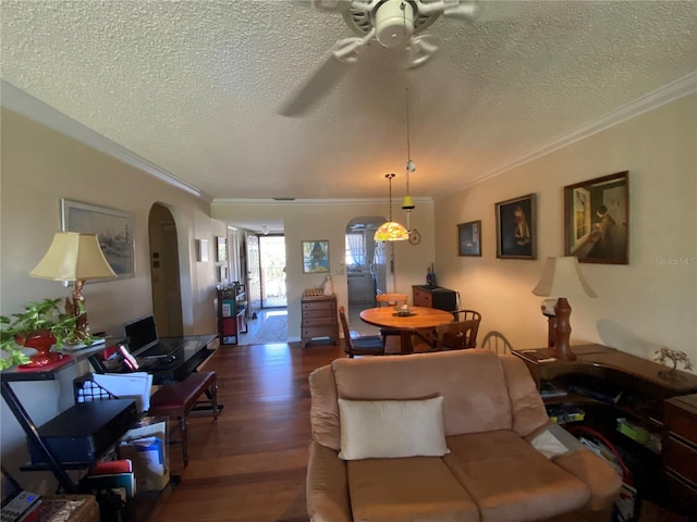 living room with dark wood-type flooring, ceiling fan, a textured ceiling, and ornamental molding