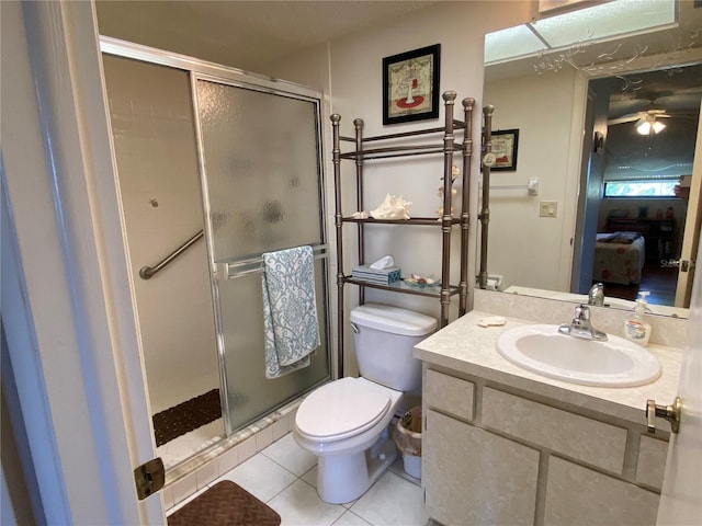 bathroom with a shower with door, toilet, ceiling fan, tile patterned floors, and vanity