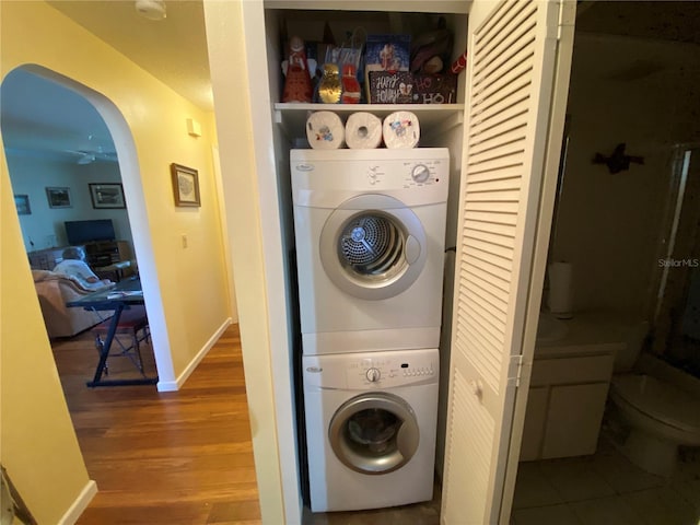 laundry room with stacked washer / dryer and hardwood / wood-style flooring