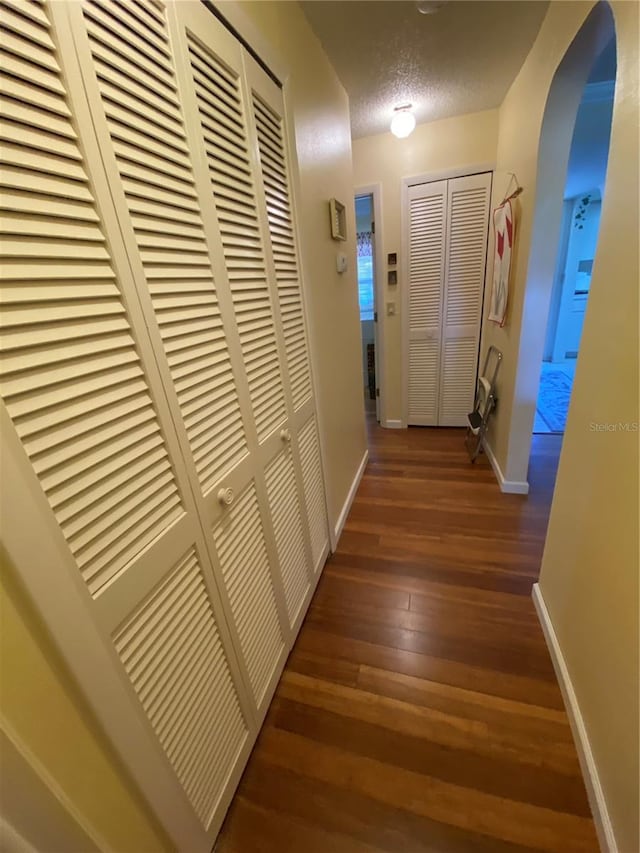 hall featuring dark wood-type flooring and a textured ceiling