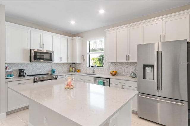 kitchen featuring light stone countertops, white cabinetry, stainless steel appliances, light tile patterned floors, and a kitchen island