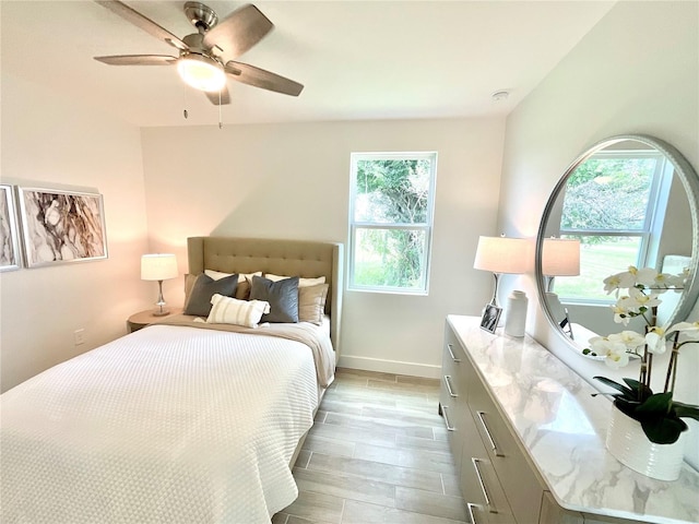 bedroom featuring light wood-type flooring, multiple windows, and ceiling fan