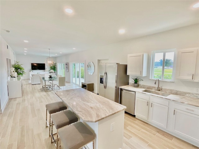 kitchen with light stone counters, sink, white cabinetry, light wood-type flooring, and appliances with stainless steel finishes