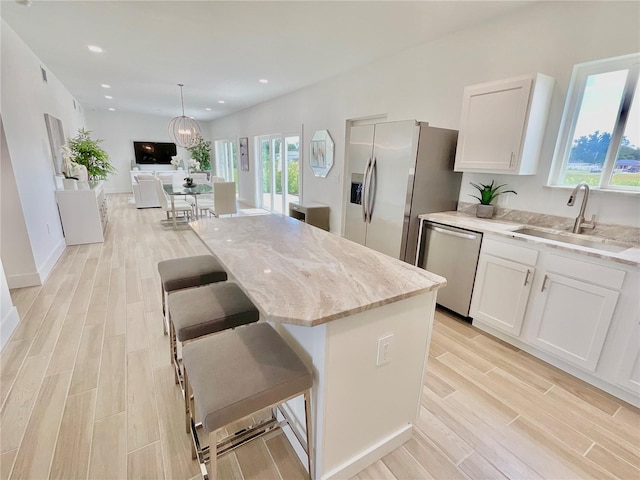 kitchen with white cabinets, light hardwood / wood-style floors, appliances with stainless steel finishes, and sink