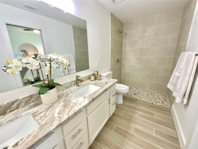 bathroom with toilet, vanity, and a tile shower